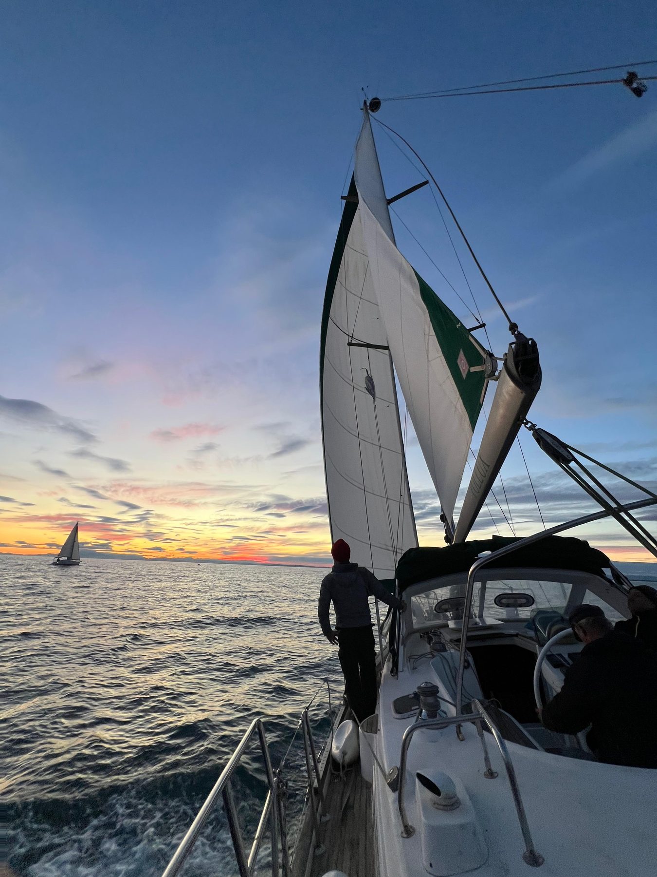The Calma's bow and genoa under a sunset sky