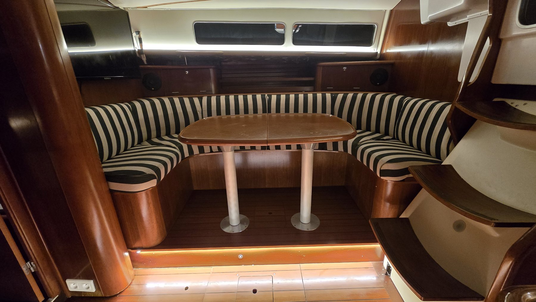 The Calma's saloon by night, U-shaped settee around the table, LED-lit