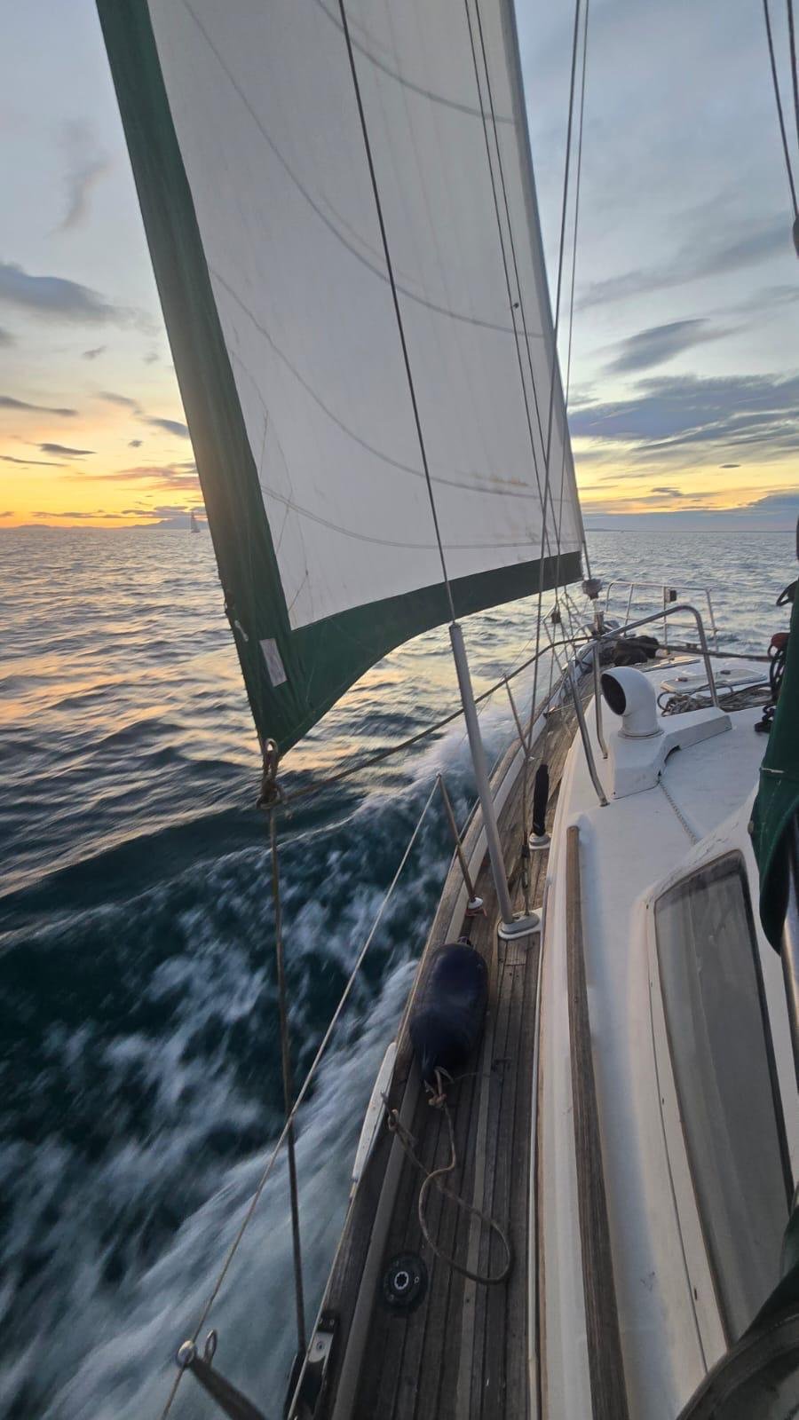 Under sail at sunset, wake along starboard rail